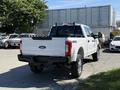 A 2017 Ford F-350 SD in white with a black bed cover and a 4x4 decal on the rear tailgate parked prominently in a lot