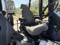 Interior of a 2013 John Deere 710K featuring a gray operator seat and control levers positioned beside the seat
