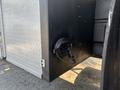A 2008 Peterbilt 340 truck with a silver diamond plate exterior and a side storage compartment featuring a coiled black wire secured to the wall