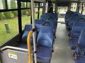 Interior view of a 2020 Chevrolet Express showing empty blue seats and a handrail with a caution sign for tripping hazards