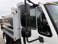 A 2012 International TerraStar truck featuring a flatbed and a large metal container attached to the rear in a white and silver color scheme