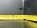 A yellow measuring tape laying flat across a surface with marked measurements showing inches next to a metal edge of a 2022 Ford F-550