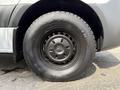 Close-up of a black wheel with a Mercedes-Benz logo on a 2021 Sprinter van showing the tire tread and alloy design