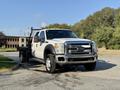 A 2014 Ford F-550 truck is parked with its flatbed visible front view showcasing its white body and chrome accents