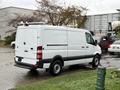 A 2017 Mercedes-Benz Sprinter van in white with a high roof and double rear doors parked on a paved surface with a cargo area equipped with a ladder rack