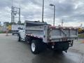 A 2011 Dodge Ram 5500 with a dump bed raised displaying a gray metal truck bed and white cab