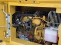 Close-up view of the engine compartment of a 2022 Caterpillar 306 featuring yellow components and various hoses and wiring