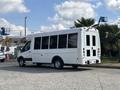 A 2018 Ford Transit-350 with a white exterior has large windows on the sides and back, featuring a high roof and a short wheelbase designed for passenger transport