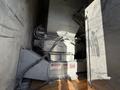 A 2011 Freightliner M2 106 with a large gray machine visible in the truck's cargo area featuring various warning labels and connected pipes