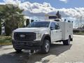 A 2024 Ford F-550 truck with a white exterior and a service body equipped with tools and equipment on the bed