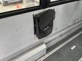 A black mesh storage bag is mounted on the wall of a bus interior, designed to hold items securely in place