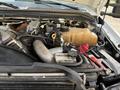 A close-up view of the engine compartment of a 2010 Ford F-550 with various components including hoses a coolant reservoir and an air intake system