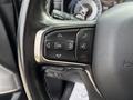 Close-up of a steering wheel with control buttons for phone, voice recognition, and cruise settings in a 2021 RAM 1500