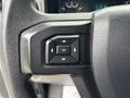 Close-up of a steering wheel control panel from a 2020 Ford F-150 featuring directional buttons and an OK button