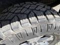 Close-up of a rugged tire with deep treads mounted on a black wheel specifically designed for a 2014 Ford F-150
