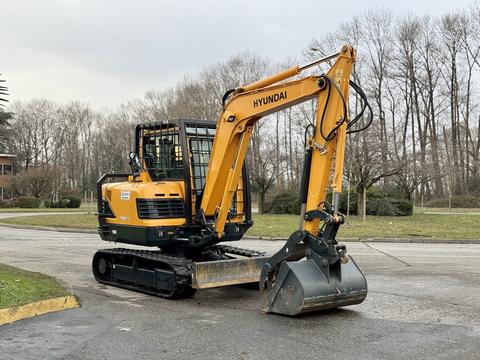 A 2022 Hyundai R55-9A compact excavator with a yellow and black exterior and a digging bucket attached at the front