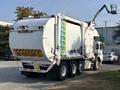 A 2011 Autocar Xpeditor garbage truck with a white body and a rear loading compartment is parked showing its back and side features