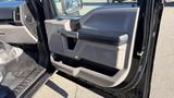 The interior door panel of a 2016 Ford F-150 featuring a black and gray design with a handle and storage compartment