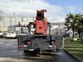 A 2010 International 4300 with a flatbed and a red crane attachment at the rear facing forward