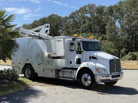 A 2009 Kenworth T270 truck with a white exterior and utility equipment on the back, featuring an elevated platform and yellow warning lights