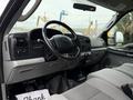 Interior of a 2006 Ford F-450 SD featuring a gray dashboard steering wheel and seats with controls and gauges visible