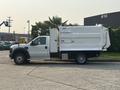 A 2009 Ford F-550 truck with a white utility body parked sideways showcasing its side profile and front design