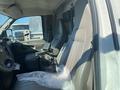 Interior of a 2011 Chevrolet Express showing the driver's seat and console area with a plastic cover on the floor