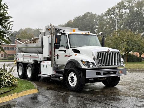 A 2011 International 7500 truck with a white body and gray accents equipped with a large rear bed for hauling materials