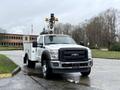 A 2012 Ford F-450 Super Duty truck with a white utility bed and a yellow lift apparatus mounted on the roof