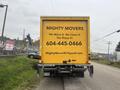 A yellow Hino 155 truck with the business name "Mighty Movers" and contact information displayed prominently on its back