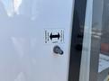 A close-up of a Chevrolet Express vehicle with a label indicating the function of a switch for opening and closing a door or compartment