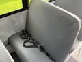 A single gray bus seat with seatbelts attached to it, featuring a textured surface and a simple design