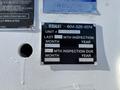 A metal information plate attached to a vehicle displaying inspection details and contact information for Versalift including a unit number and inspection due dates