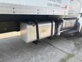 A metallic fuel tank mounted on the side of a 2012 Hino 338 truck with visible straps and a pipe connection