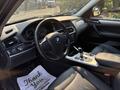 Interior view of a 2013 BMW X3 featuring a black leather steering wheel dashboard controls and gear shift console