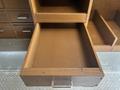 A wooden drawer with no contents pulled out from a cabinet showcasing its smooth interior and metal handle