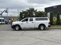 A white 2013 RAM 1500 pickup truck with a cap is parked, featuring chrome wheels and a simple design