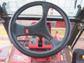 Steering wheel and control console of a 2013 Toro Grounds Master 5910 featuring a black wheel and various operational buttons in red and black