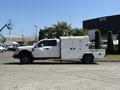 A white 2017 Ford F-550 utility truck with a closed service body and multiple compartments on the side