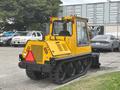 A yellow 2004 Bombardier SW48 tracked utility vehicle with a cab and rear plow attachment parked in a lot