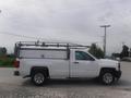A 2015 Chevrolet Silverado 1500 pickup truck in white with a ladder rack on the roof and a utility bed in the rear