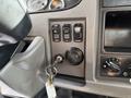 Close-up of the control panel of a 2015 Peterbilt 337 showing various buttons including cruise control and a key ignition