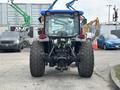A 2009 New Holland T4020 tractor viewed from the rear showcasing large rear tires and a compact design with visible hydraulic connections and taillights