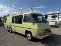 A 1976 GMC Motorhome in a light yellow color with distinctive rounded edges large windows and three axles visible