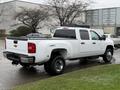 A white 2013 Chevrolet Silverado 3500HD truck with a crew cab and bed visible from the rear angle showcasing its wheels and tailgate design