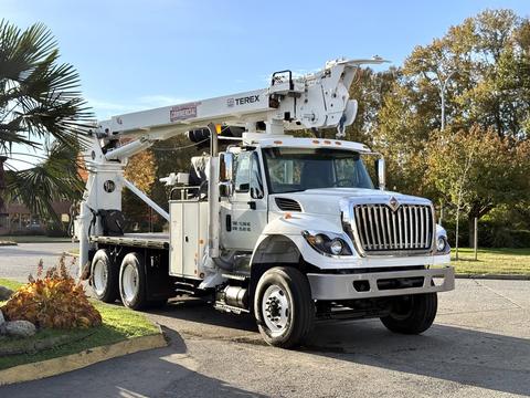 A 2011 International 7500 bucket truck with a white and silver exterior and elevated boom arm for reaching high places