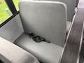 A gray upholstered bus seat with a black seatbelt lying across it
