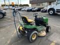 A green and yellow 2021 John Deere L Series S lawn mower with a steering wheel and attached hose for cleaning or maintenance