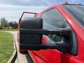 A red 2013 Ford F-550 with a large side mirror designed for towing and a robust build suitable for heavy-duty work