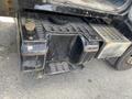 A black fuel tank with a circular cap and a checker plate surface mounted on the side of a 1996 GMC Top Kick truck
